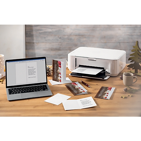 Laptop and printer on a desk surrounded by greeting cards and decoration.