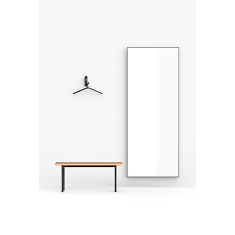 Pièce lumineuse avec banc, miroir, porte-manteau. Le miroir et le mur sont blancs. Le banc a un plateau en bois avec des pieds noirs.