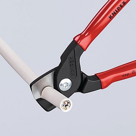 Pince coupante Knipex rouge coupant un câble. La section transversale du câble est visible.