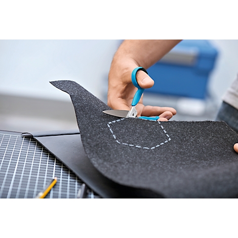 Mains coupant du feutre gris avec des ciseaux bleus le long d'une ligne pointillée.