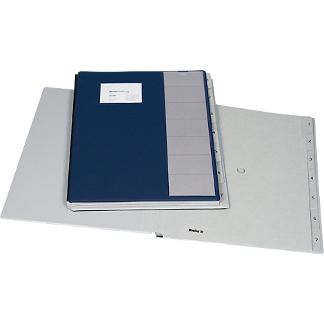 Un classeur ouvert avec une couverture bleue repose sur un dossier gris.