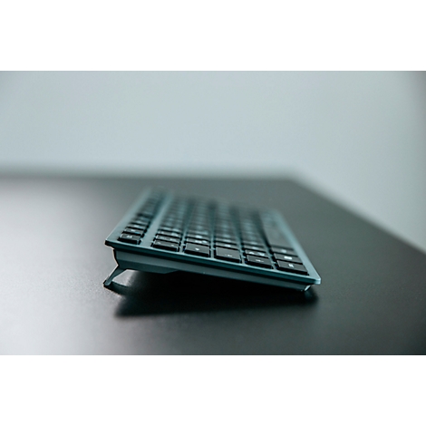 Gros plan en perspective d'un clavier gris sur une table sombre. Le clavier est légèrement incliné.