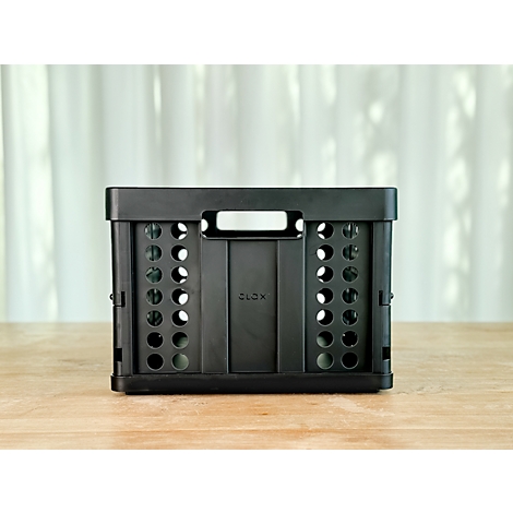 Black, foldable box with holes, text 'CLOX' on wooden surface. A light curtain in the background.