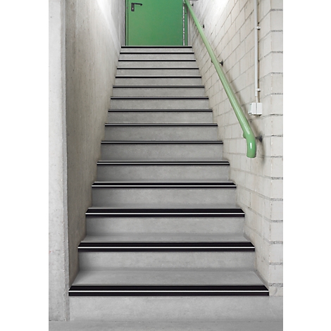 Stairs with gray steps, black stripes and a green handrail. At the end of the stairs is a green door.