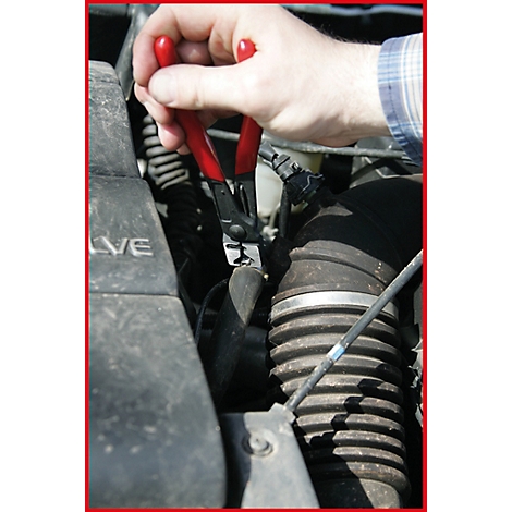 Person hält rote Zange an einem Motor.