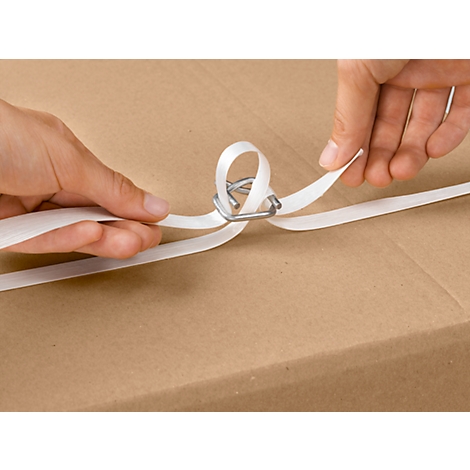Hands tighten a white strap around a cardboard box using a metal clip.