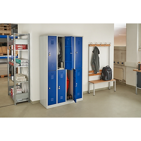 Blue lockers with open doors, clothing and items. Next to it is a coat rack with a jacket and backpack.