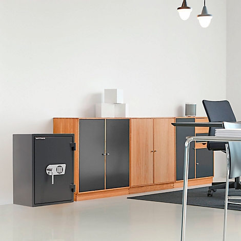 Un coffre-fort noir dans un bureau, avec des armoires et un bureau derrière.