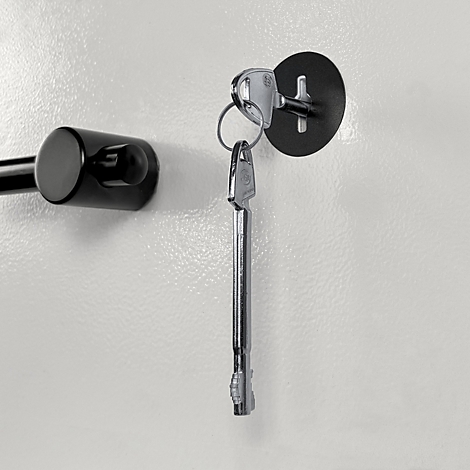 Une clé argentée est insérée dans une serrure noire ronde sur une surface claire et lisse.