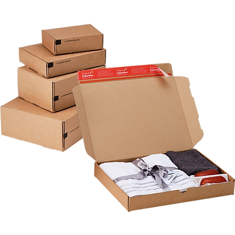 Coffret cadeau ouvert avec serviettes et savon, à côté de boîtes empilées.