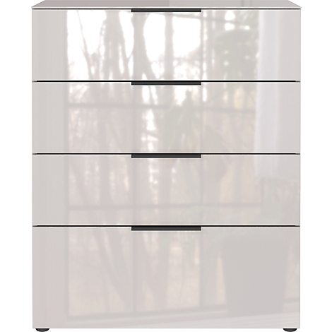 Commode blanche brillante avec quatre tiroirs et des poignées noires. Reflets d'arbres sur la surface.