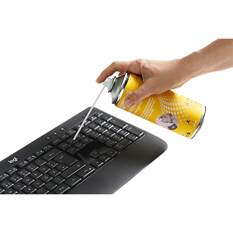 A hand sprays cleaning foam from a yellow can onto a black computer keyboard.