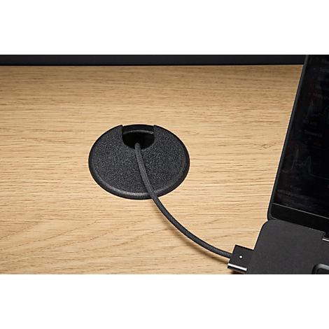 Gros plan d'une surface de bureau avec un passe-câble et un ordinateur portable connecté.