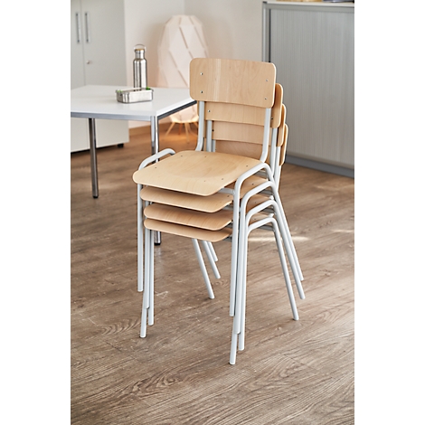 Stacked chairs with light wood and white metal frames. In the background a table and a cabinet.