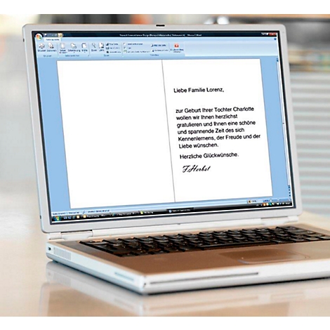 Laptop showing a greeting card: "Dear Family Lorenz" on the birth of Charlotte. Text below. Signature F. Herkst.