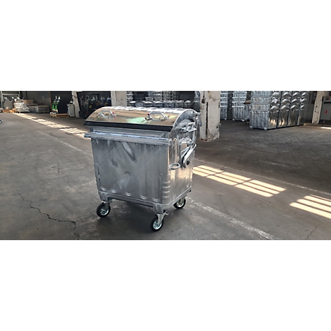 Un contenedor de basura de metal plateado con ruedas se encuentra en un almacén.