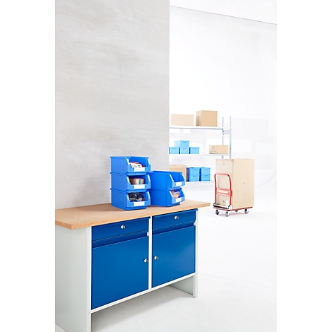 Conjunto de armario para herramientas azul con contenedores de herramientas azules en la encimera. Cajas y carrito en el fondo.