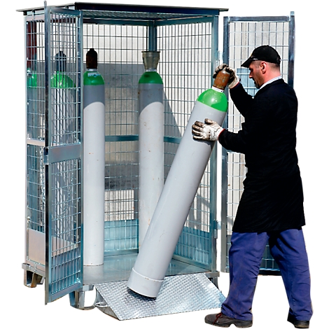 Un homme charge des bouteilles de gaz dans une cage en acier roulante. Une bouteille est en cours de chargement dans la cage, tandis que deux autres sont déjà à l'intérieur.