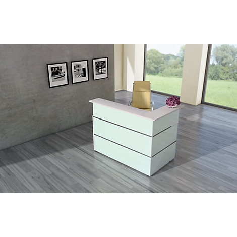 Bright reception desk against a gray wall, three black and white pictures, chair and flowers. Large windows overlooking nature.