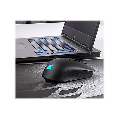 Schwarze Gaming-Maus mit leuchtendem Logo neben Laptop. Hintergrundgraue OberflÃ¤che und beleuchtete Tastatur.
