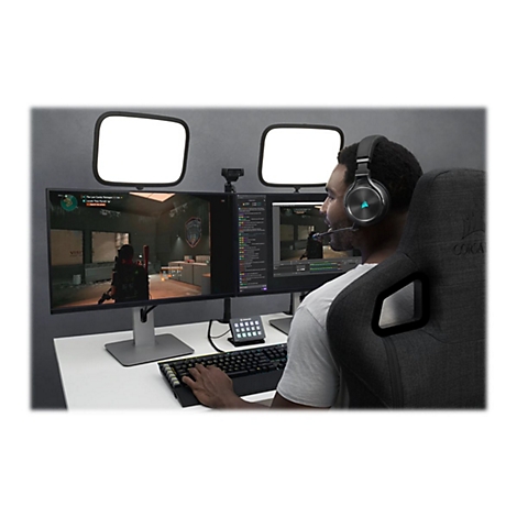 Ein Mann sitzt an einem Schreibtisch mit zwei Monitoren, einem Headset und einer Tastatur. Er spielt ein Videospiel und streamt es.