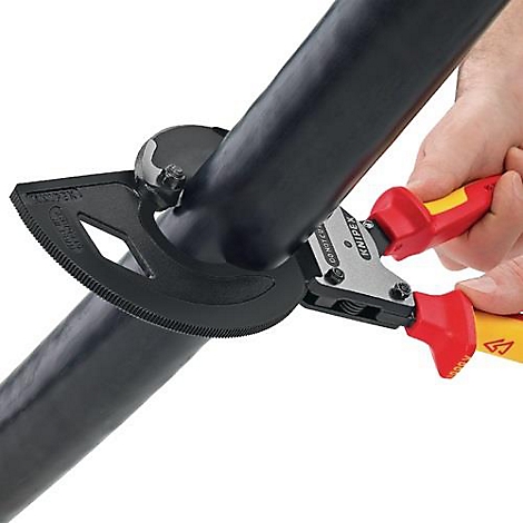Personne coupant un câble noir avec une pince. L'outil a des poignées rouges et jaunes et un guide noir.
