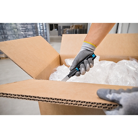 Personne coupant l'emballage avec un couteau. Les gants protègent les mains.