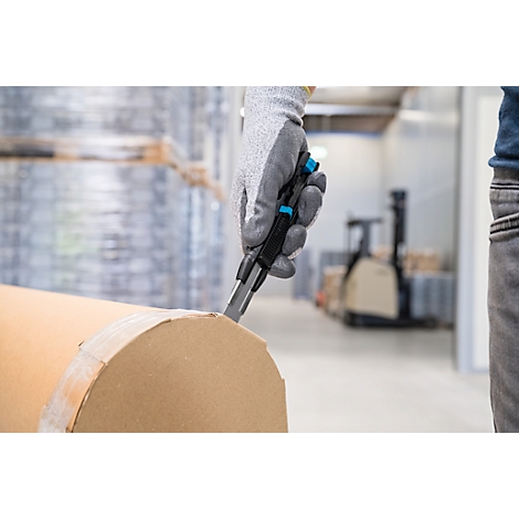 Une main gantée coupe un rouleau de carton avec un cutter. Un chariot élévateur en arrière-plan.