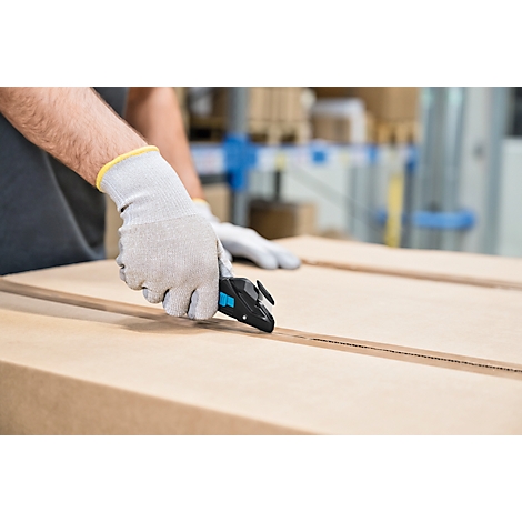 Une personne portant des gants de travail gris ouvre un carton avec un couteau de sécurité noir.