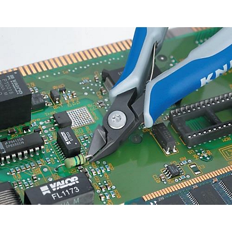 Une pince coupante coupe un fil sur une carte de circuit imprimé verte. Poignée bleue, logo "KNIPEX" visible.