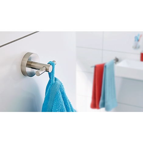 Un porte-serviettes métallique est accroché à un mur blanc ; une serviette bleue y est accrochée.
