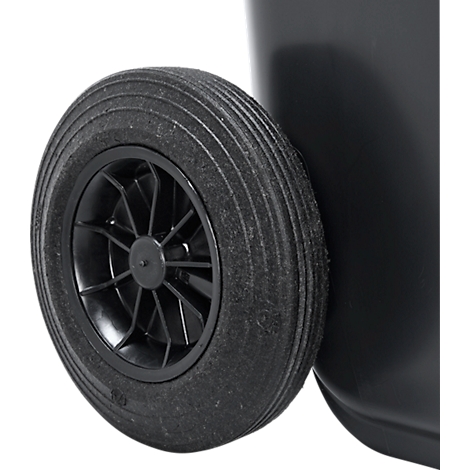 Primer plano de una rueda negra en un cubo de basura negro. La rueda tiene un cubo de radios negro y un neumático negro con banda de rodadura.