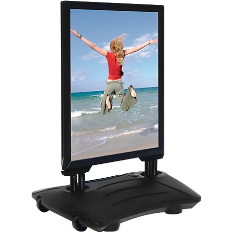 Advertising sign with a picture of a woman jumping on the beach. Black frame, black base with wheels.