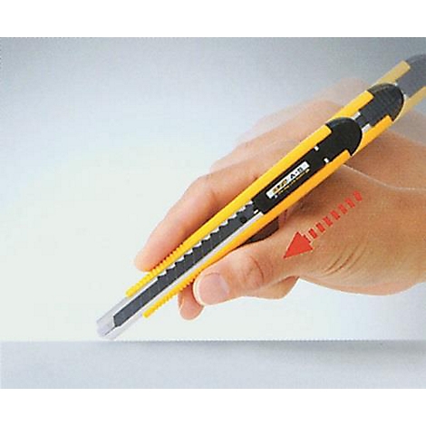Une main tient un cutter jaune et coupe du papier. Une flèche rouge indique la direction de la coupe.