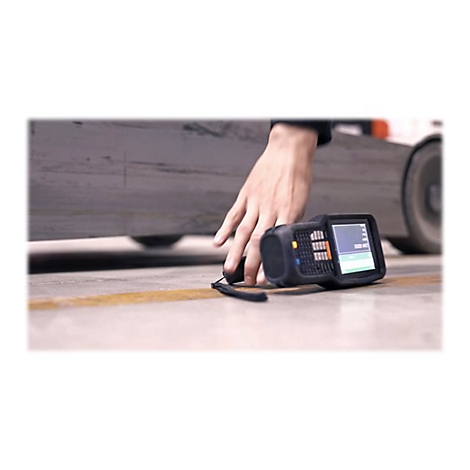 Hand hält einen Scanner auf einem Industrieboden, im Hintergrund ein Gabelstapler.