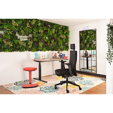 Büro mit Schreibtisch, Stuhl, rotem Hocker und Wand mit Pflanzen. Spiegel und Dekorationen sind sichtbar.