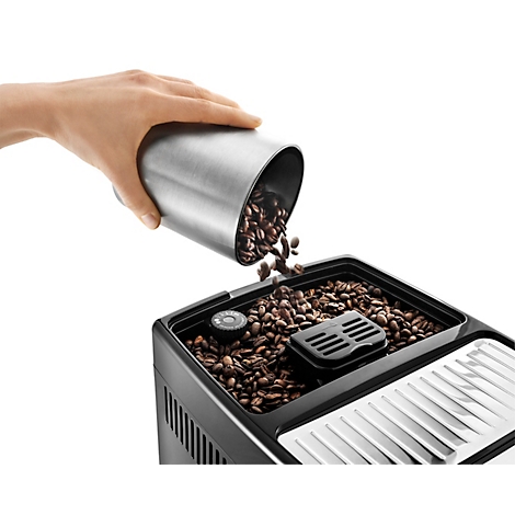 Person schüttet Kaffeebohnen aus einem Metallbehälter in den Bohnenbehälter einer Kaffeemaschine.