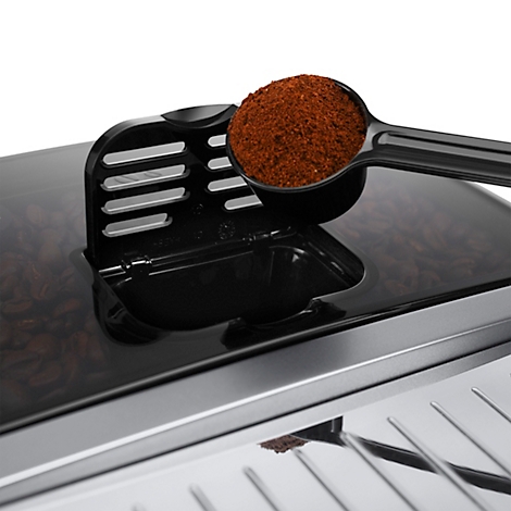 Nahaufnahme einer Kaffeemaschine. Ein Löffel mit Kaffeepulver wird in einen Behälter gefüllt.