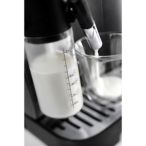 Milchbehälter einer Kaffeemaschine mit Skala füllt Milch in ein Glas.