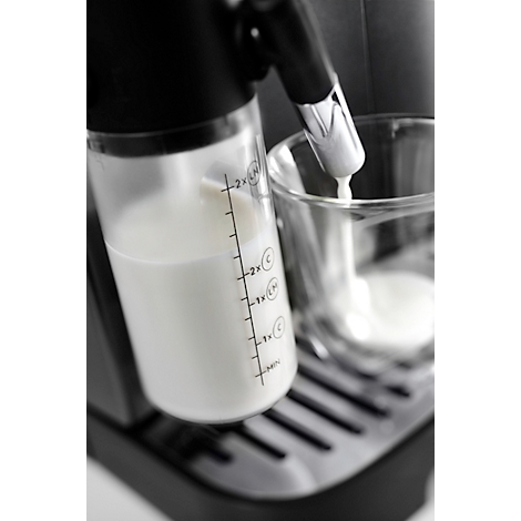 Milch wird in ein Glas gefüllt, Detailaufnahme von einer Kaffeemaschine.