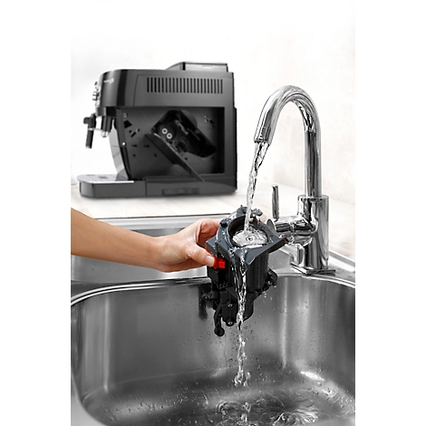 Eine Person reinigt ein schwarzes Teil einer Kaffeemaschine unter fließendem Wasser.