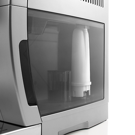 Gros plan d'une machine à café argentée. Le réservoir d'eau montre un filtre.