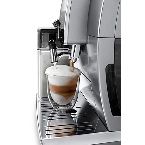 Machine à café remplissant un verre de latte macchiato avec du lait et de l'espresso.