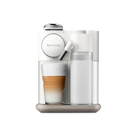 Een witte koffiemachine met melkopschuimer en een glas latte macchiato. Het Nespresso-logo staat op de machine.