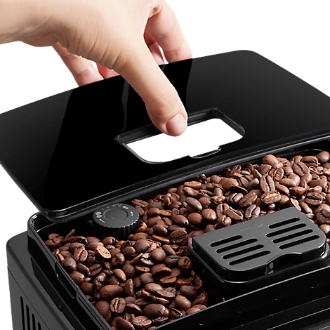Close-up van een hand die het deksel opent van een zwarte koffiemachinecontainer gevuld met koffiebonen.