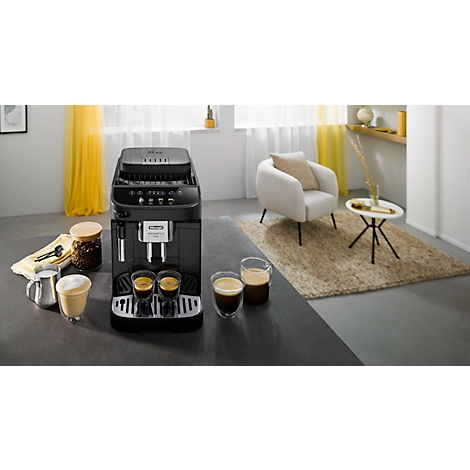 Zwarte De'Longhi Magnifica Start espressomachine op een aanrecht met koffieglazen in een gezellige kamer.