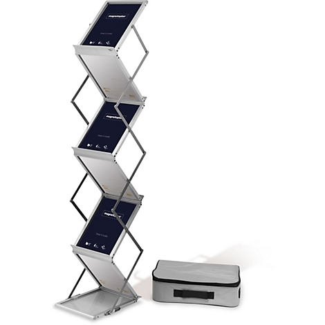 Un présentoir de brochures pliable argenté avec plusieurs compartiments. Sur les panneaux, on peut lire "magnetoplan Design & Qualität". Un sac de transport gris est à côté.