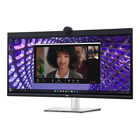 Un moniteur Dell avec une webcam intégrée affiche un appel vidéo. Une femme aux cheveux bouclés parle, avec deux autres participants visibles dans la fenêtre. L'arrière-plan de l'écran est un motif abstrait.