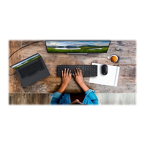 Vue aérienne d'un bureau avec un ordinateur portable, un clavier, une souris et un écran. Personne tape sur le clavier. Un paysage est visible sur l'écran.