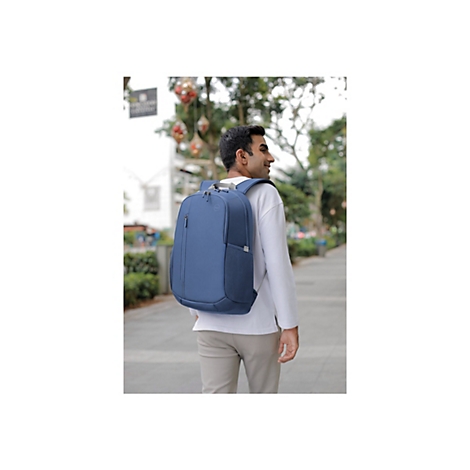 Ein Mann mit blauem Rucksack, geht im Park spazieren, lÃ¤chelnd.